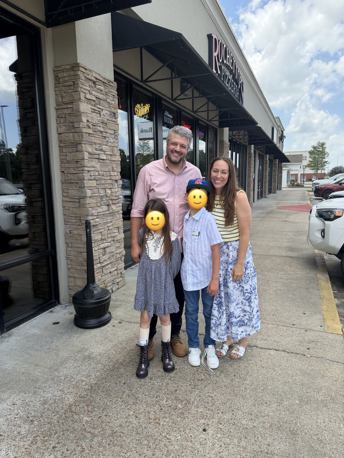 Family photo outside a pizza restaurant with smiley faces over the kids